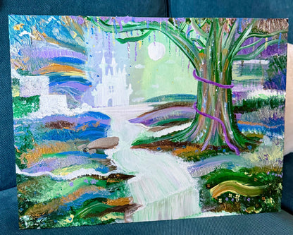 A colorful painted artwork depicting a whimsical landscape with a white castle, a large tree, a winding stream, and pastel sky tones, displayed on a teal couch.